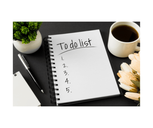 To do List and numbers written on notepad with coffee, small plant and pen around it on a table